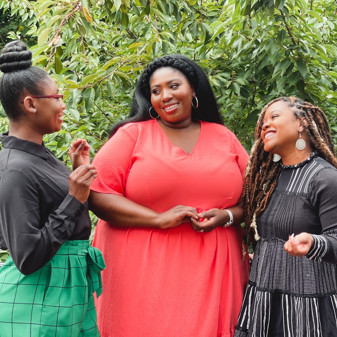 Three neighbours in conversation, laughing together under a tree