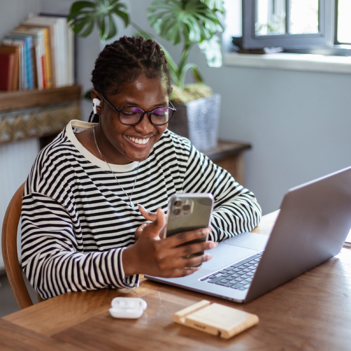 A woman at her dining table with a laptop and phone, reviewing a property purchase from abroad